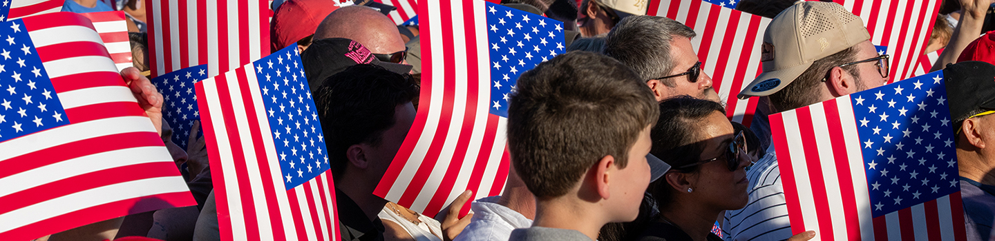Attendees dressed in red, white and blue raise cardboard American flags during the Great American State Fair’s kickoff celebration.